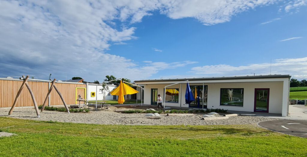 Sandspielbereich mit Schaukel, Findlingen und Holzstämmen