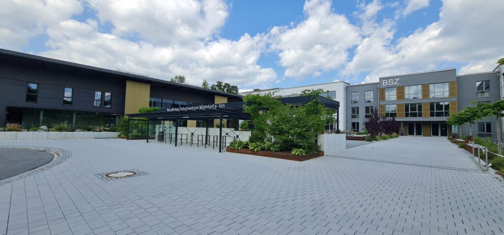 Haupteingang und Aufenthaltsbereich, teils bewachsene Pergola, Pflanzbeete und Fahrradstellplätze