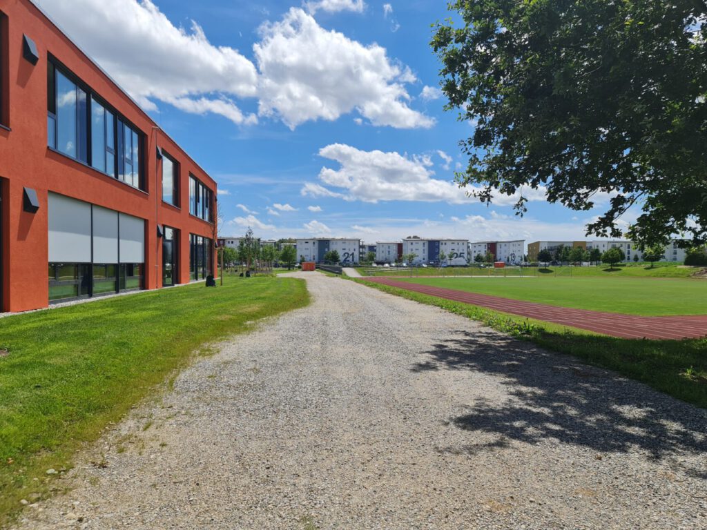 Schotterfläche als Zufahrtsmöglichkeit, zwischen Schule und Sportplatz