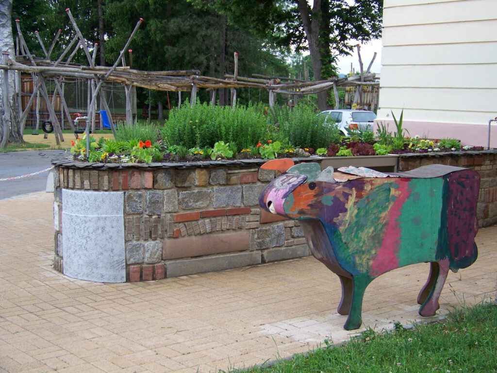 Hochbeet gemauert aus verschiedenen Materialien, farbige Tierskulptur