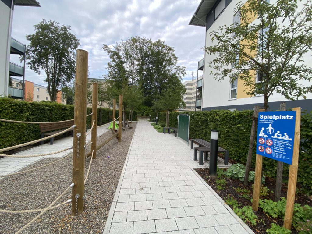 gepflasterter Weg und Spielmöglichkeiten aus Holzpfosten